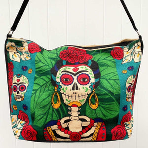 Day of the Dead Frida Kahlo skeleton design in green, blue, black, and red, silkscreened on cotton handbag.with black cotton strap, shown against white background.