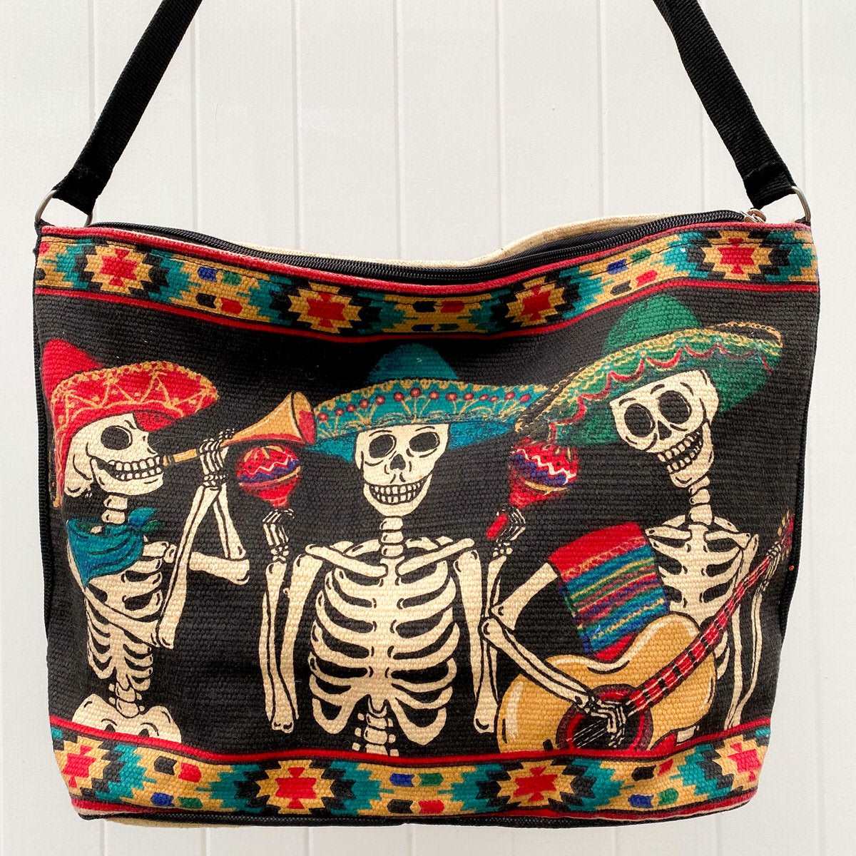 Day of the Dead Tres Amigos skeleton design in black, red, yellow and green, silkscreened on cotton handbag with black cotton strap, shown against white background.