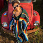 Woman draped in green and multi-color striped Mexican Southwest blanket standing in front of vintage VW Beetle