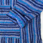 Closeup of hoodie pocket and sleeve woven in stripes of dark blue, light blue, and white