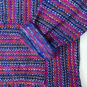 Closeup of hoodie pocket and sleeve woven in stripes of pink and cobalt blue