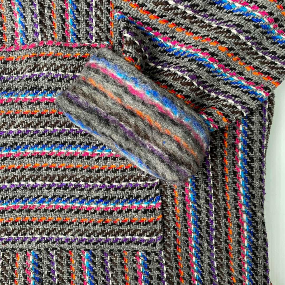 Closeup of hoodie pocket and sleeve woven in gray with stripes of blue, pink, orange and black