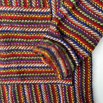 Closeup of hoodie pocket and sleeve woven in stripes of dark purple, blue, yellow, red and white