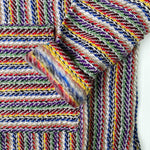 Closeup of hoodie pocket and sleeve woven in stripes of bright colors with grey and white
