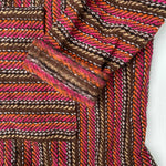 Closeup of hoodie pocket and sleeve woven in stripes of pink, orange, and brown