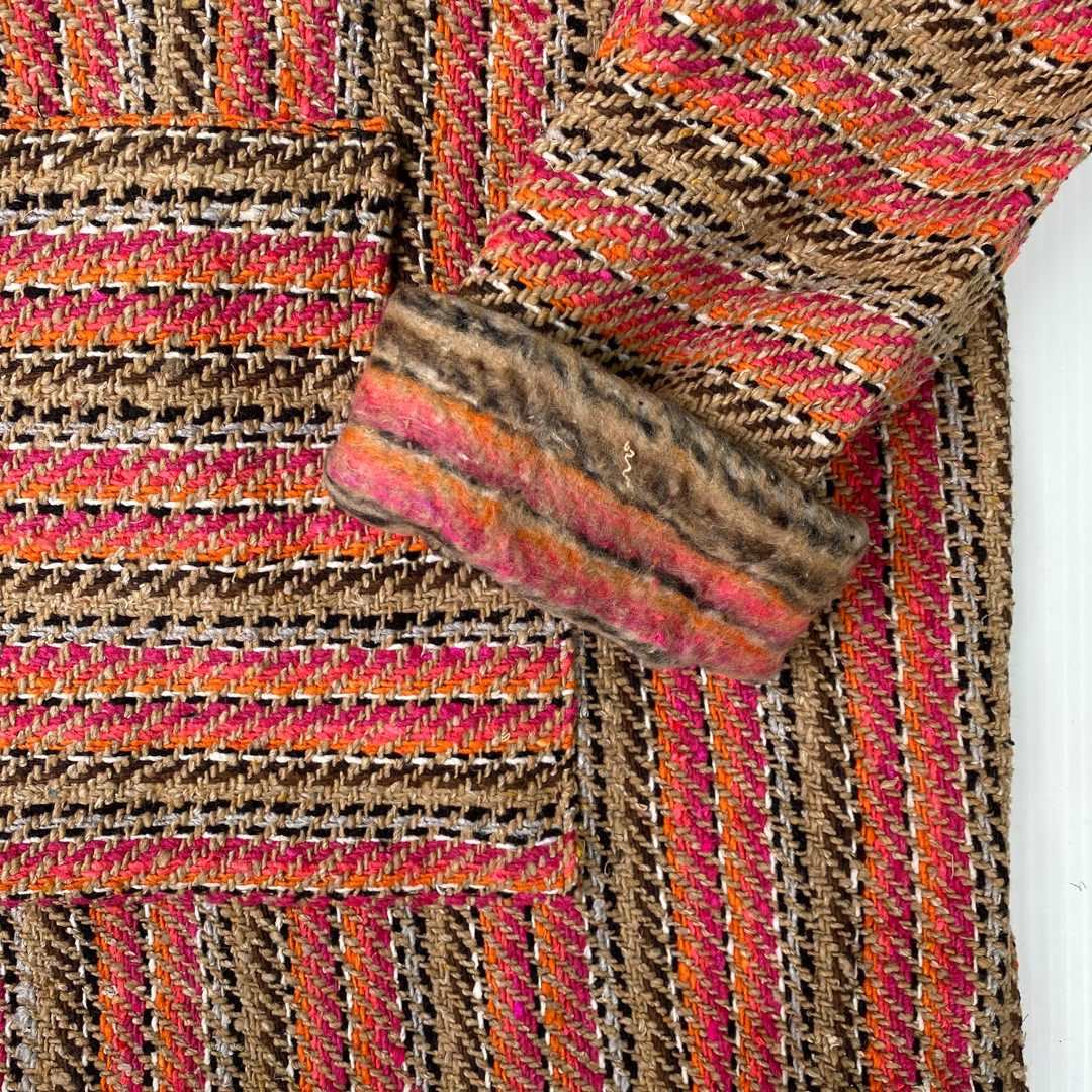Closeup of hoodie pocket and sleeve woven in stripes of pink, orange, and tan