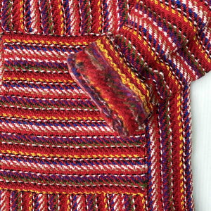 Closeup of hoodie pocket and sleeve woven in red with stripes of white, blue, yellow and tan