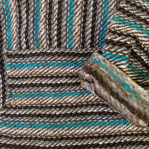 Closeup of hoodie pocket and sleeve woven in shades of teal and brown with white