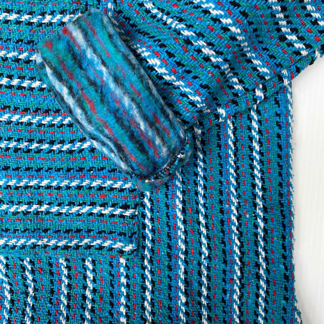 Closeup of hoodie pocket and sleeve woven in stripes of turquoise and white 